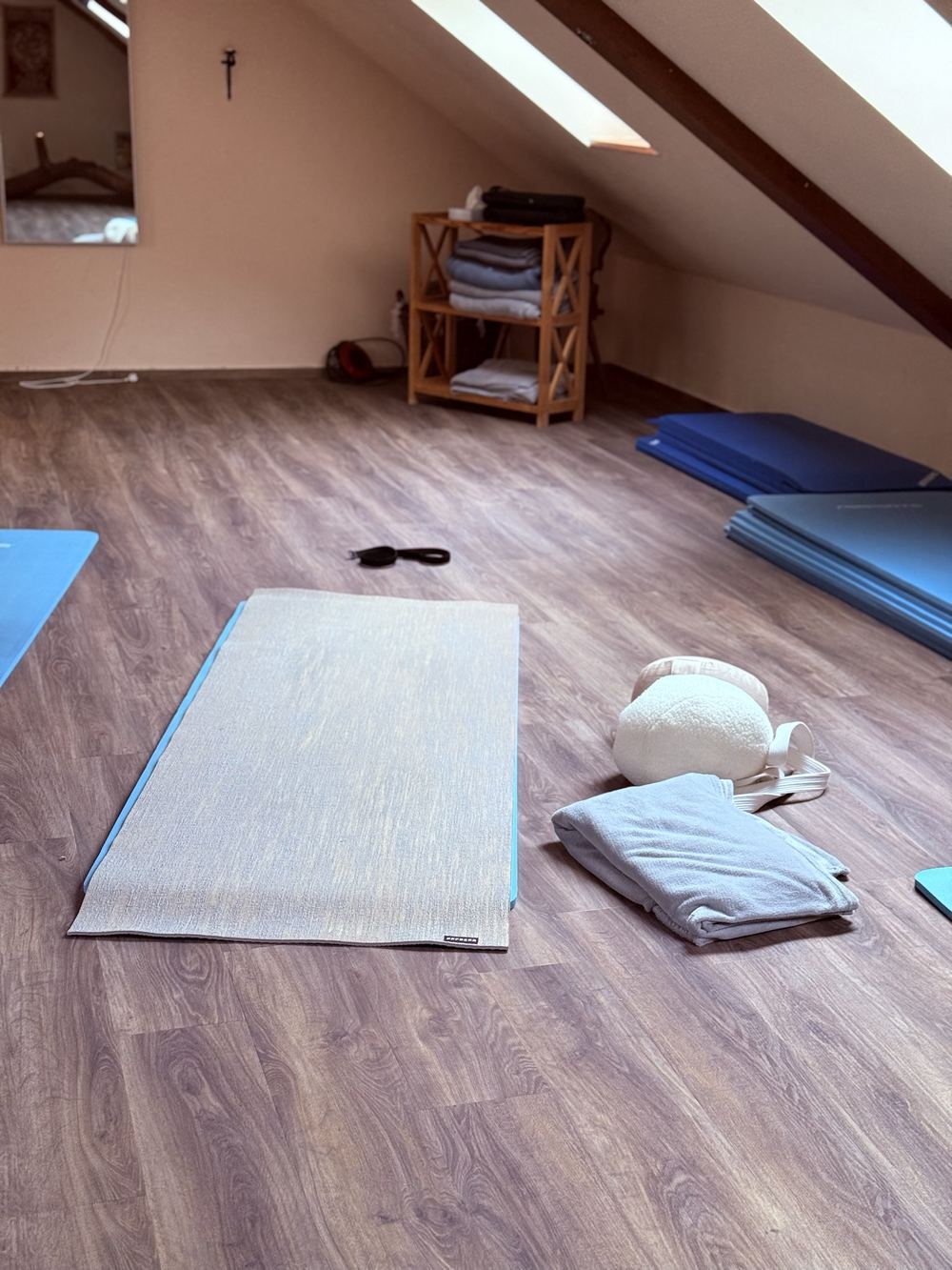 Eine ausgerollte Yogamatte mit gefalteter Decke und rundem Meditationskissen